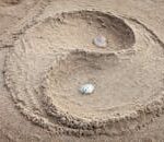 A yin yang design sculpted in sand with seashells at Isla Canela beach, Spain.